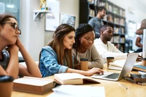 Shot of two young women using a laptop together in a college library Shot of two young women using a laptop together in a college library
